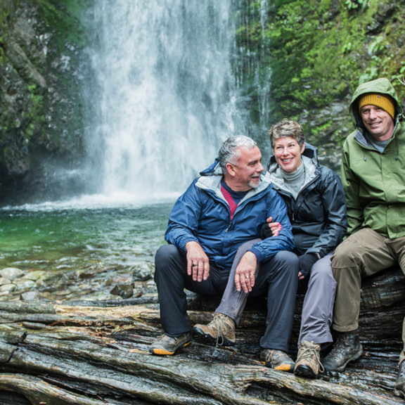 Four people sitting infront of waterfall 